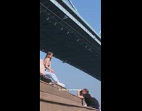 Woman sits on steps and takes pictures under bridge