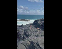 Woman in swimsuit and skirt poses on Hawaiian rocks 