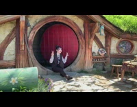Woman puts peace signs up in front of hobbit hole and takes picture
