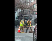 Two construction men pull rope from manhole