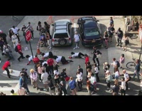 Four women crawls on hands and knees on street through crowd