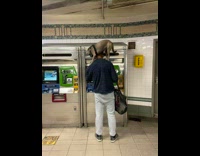 Man balances dog on shoulder while using ticketing machine