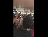 Crowd of teens sing song together and record themselves on subway train