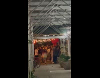 Crowd of people dance outside on sidewalk 