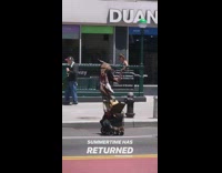 Guy wearing Native American headpiece dances and twirls baton around on the street