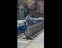 Guy uses blue rental bicycle to exercises 