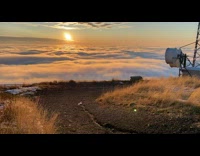 View of the sunset with the clouds below on top of the mountain