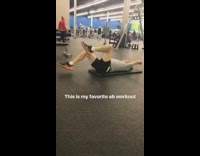Man lays on yoga mat and flails arms and legs in the air at gym