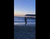 Guy dances with dumbells on beach 