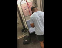 Guy exercises on the subway and does bicep curls with resistance band on handrail