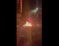 Burning car on street night outside house