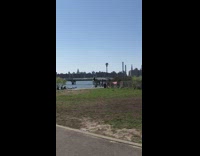 Two People Walk on Stilts in Park 