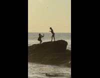 Two women in their beach wear takes turns at the rock Part 2