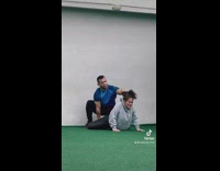 Trainer helping client stretch by pushing groin into ground