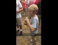 Boy takes a swig and drinks alcohol at outdoor event 