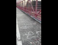 Person wears inflatable bear runs on bridge