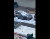 Guy removes snow on car using stick