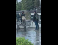 Woman in brown coat poses with feet on the bench