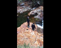 Guy stands rock waterfall blue hat 