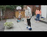 Woman falls off blue hoverboard in backyard