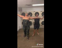 Two guys wear women clothing rompers and dance to I saw the sign pitch perfect song in laundromat