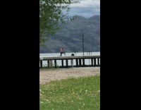 Pink shirt lady yoga stretches cement dock 