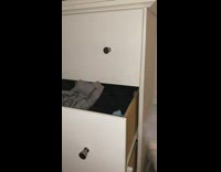 Girl shakes treats black cat inside dresser