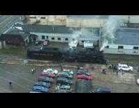 People gather around large black train steam 