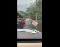 Traffic of cars drives slowly through flood 