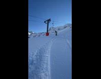Snowboarder stops in snow near lift 
