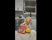 Baby standing mountain  of shredded cheese into bowl 