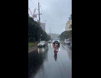 Man shirtless surfs on the rainy street