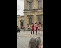 Woman red yoga outfit stretches feet upwards in public