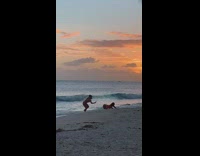 Woman pink green swimsuit bend over beach