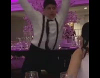 Guy wearing black suspenders dances at wedding