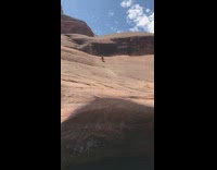 Guy slides down rock with surfboard and flies into cave pool below