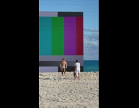 Man in boxers in front of screen at the beach