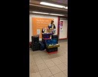 Man plays Hotel Motel on saxophone with dancing cat dolls and strobe lights at subway station