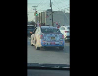 Car is covered in flags and stickers 