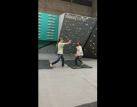 Guy doing flips off his friend at rock climbing gym