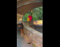 Two people red and yellow blankets under bridge