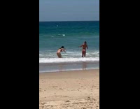 Woman in bikini poses with hands on her hair at the beach
