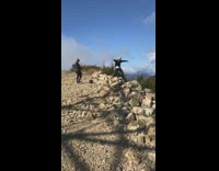 Blue backpack girl dances mountain edge rocks 