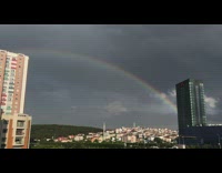 Double rainbow over city gloomy grey sky