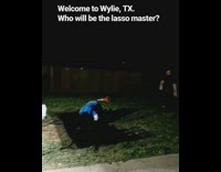 Two men play the lasso game, guy gets his leg pulled by lasso and trips over