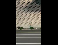 Girl wearing blue jumpsuit catwalks down sidewalk 