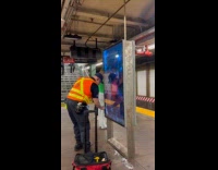 MTA employee singing while cleaning portrait screen
