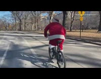Man dressed as santa rides black bike in park