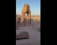 Lady in red dress poses with arch at national park 