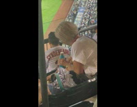 Elderly woman pours beer into water bottle at baseball game 